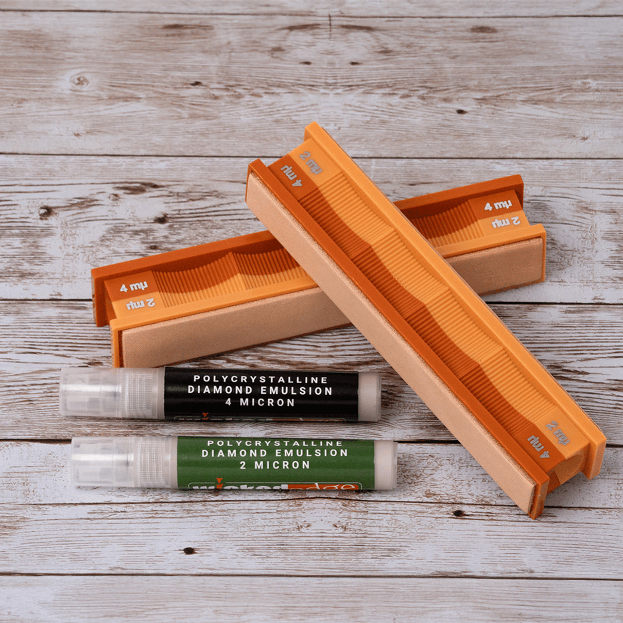 4/2 micron diamond emulsion and leather strops pack in close-up on weathered wood surface.