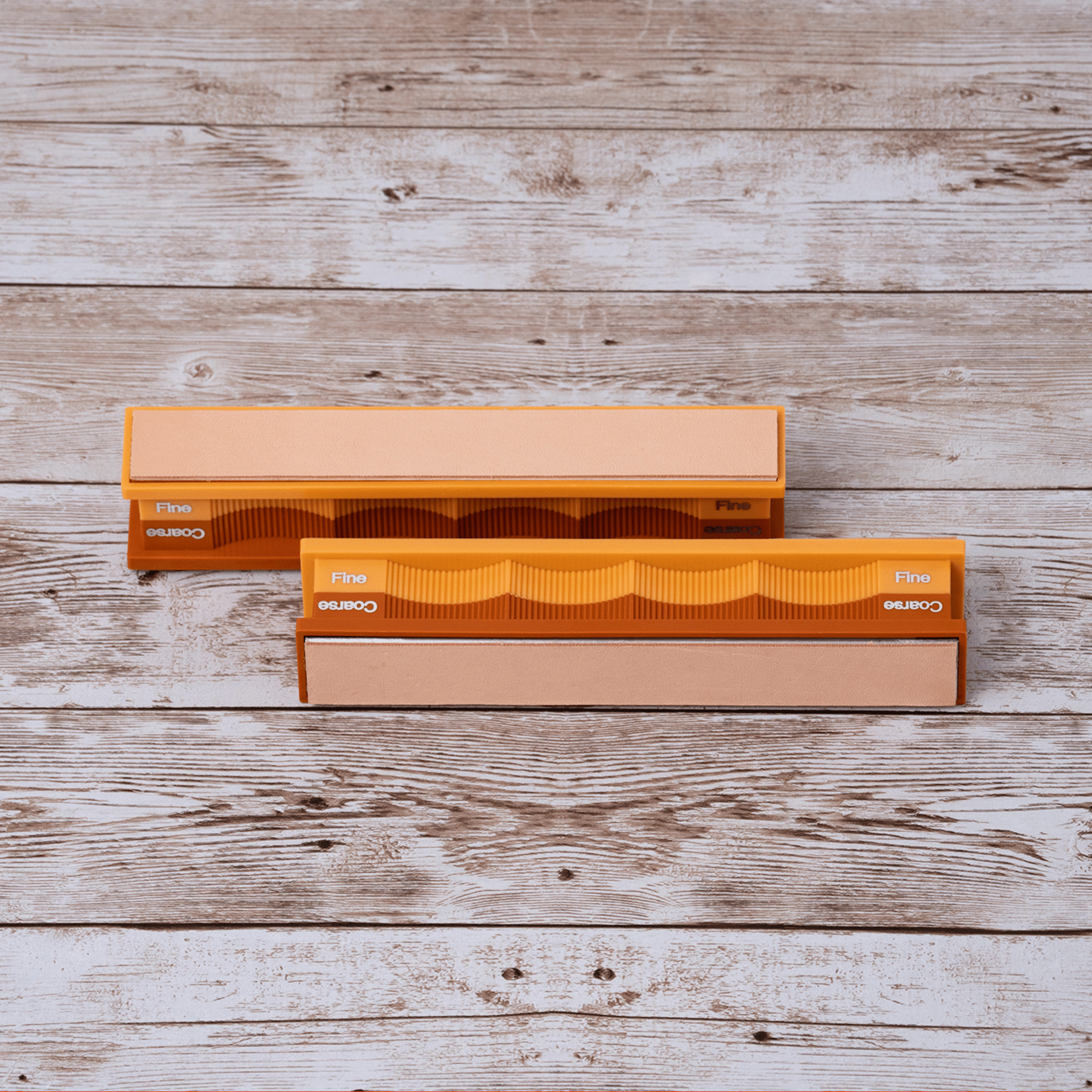 Blank kangaroo leather strops pack in orange packaging on weathered wood surface at close-up zoom from front angle.