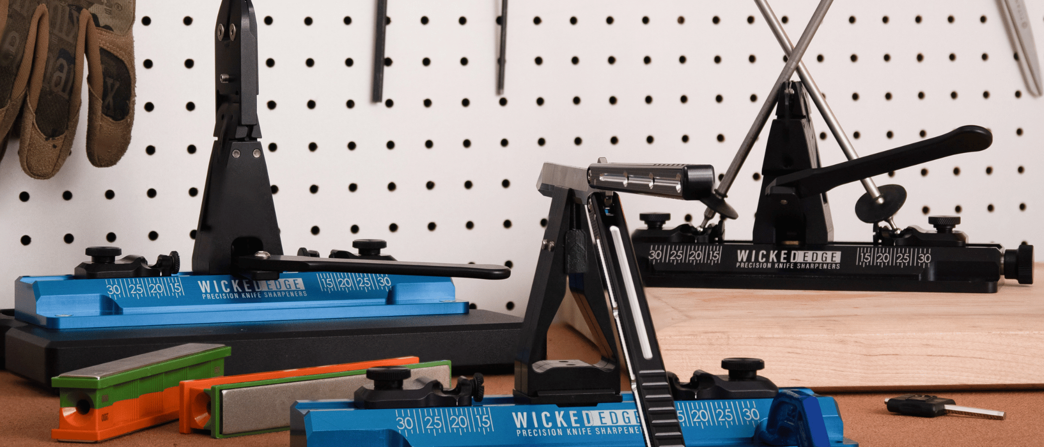 WE64 Cobalt precision knife sharpener with Wicked Edge Low Angle Adapter (left), GO WE60 precision knife sharpener with butterfly knife mounted in vise (center), and WE66 Obsidian precision knife sharpener (left)