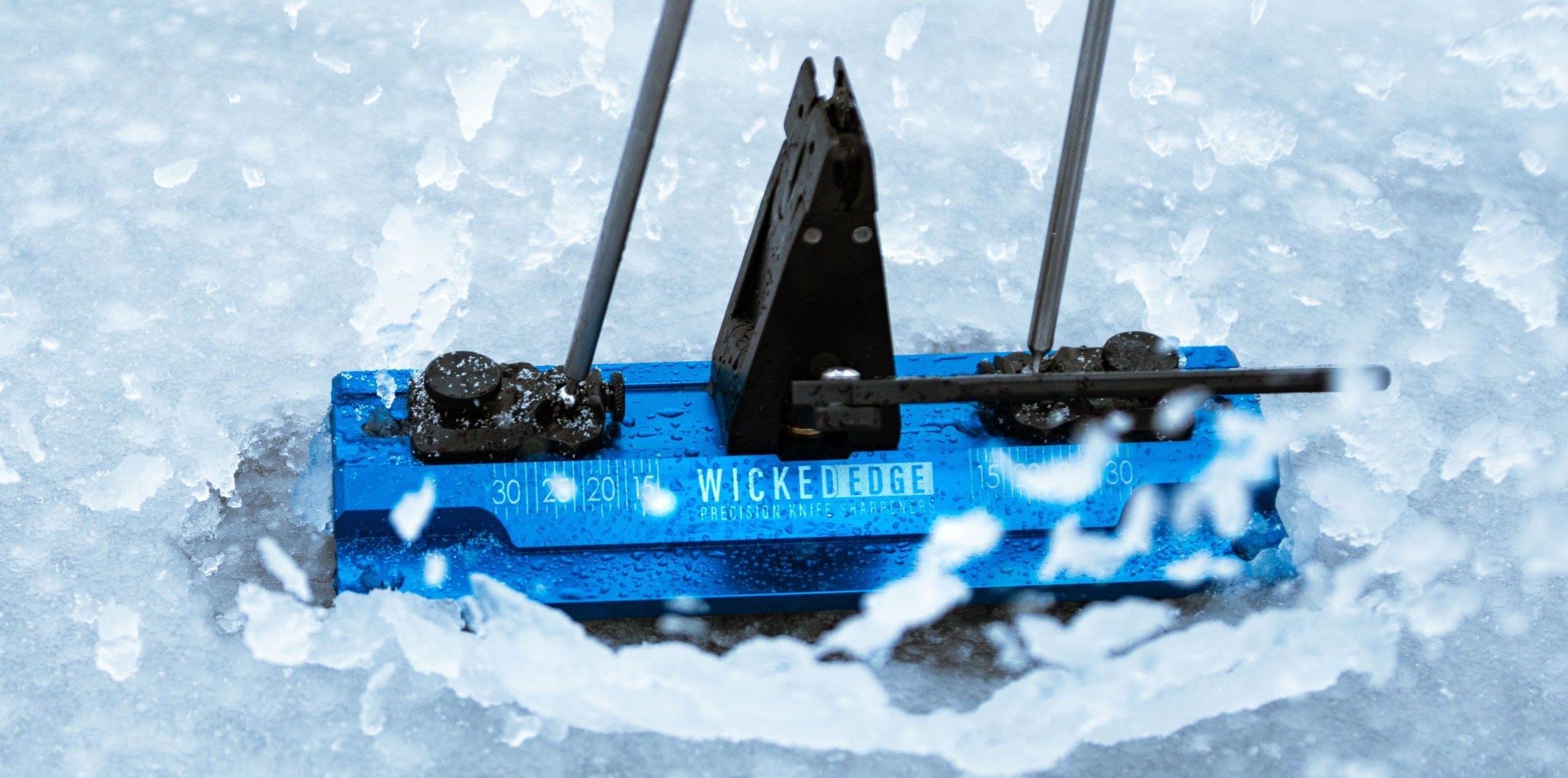 WE64 precision knife sharpener sitting snow. Front view.