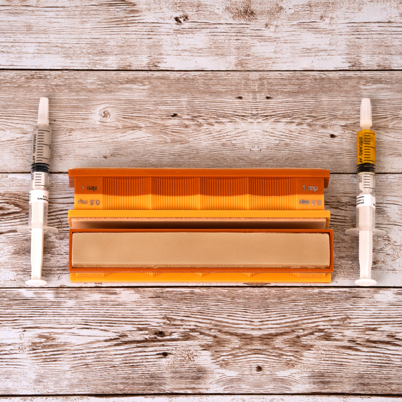 1/0.5 micron diamond and leather strops pack in close-up top-down view on weathered wood surface.