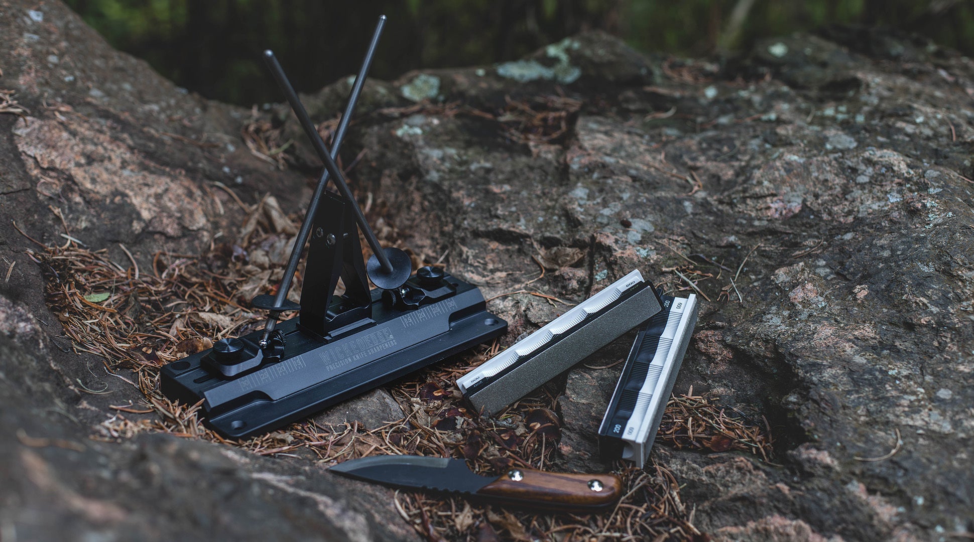 Perspective view of WE40 Carbon precision knife sharpener pictured with diamond sharpening stones and a field knife