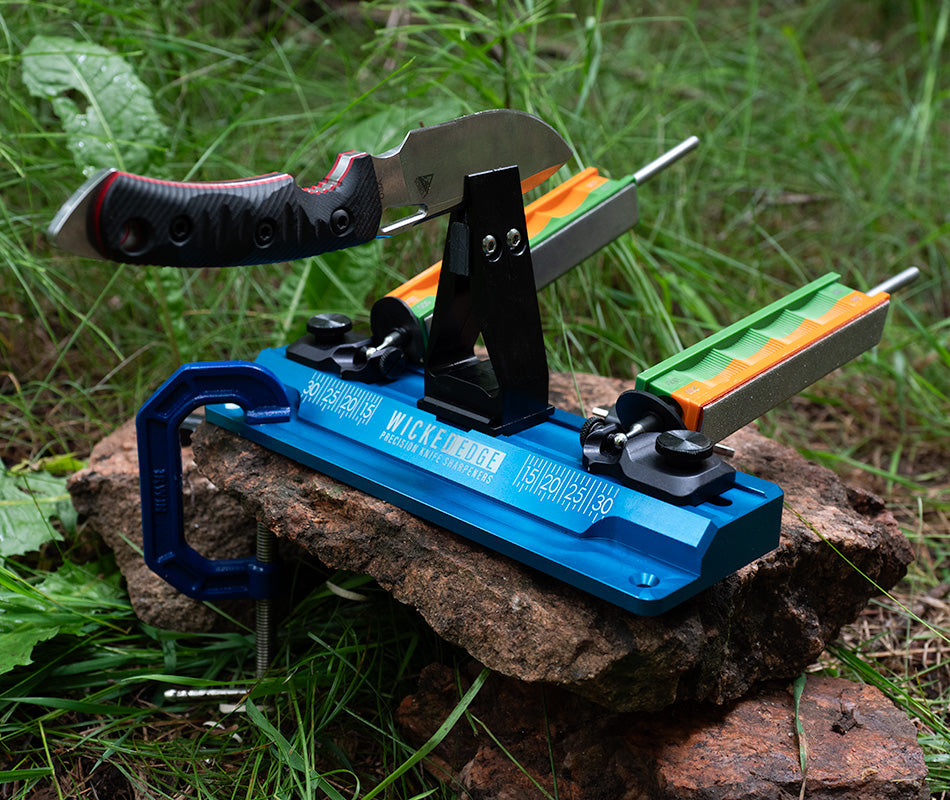 Wicked Edge GO dual-sided knife sharpener in grass at close-up from side angle.