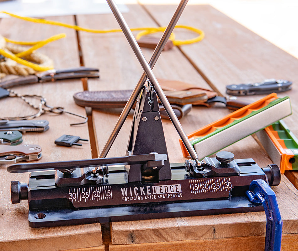 Wicked Edge Obsidian WE66 precision knife sharpener in workshop setting at close-up zoom from front angle.