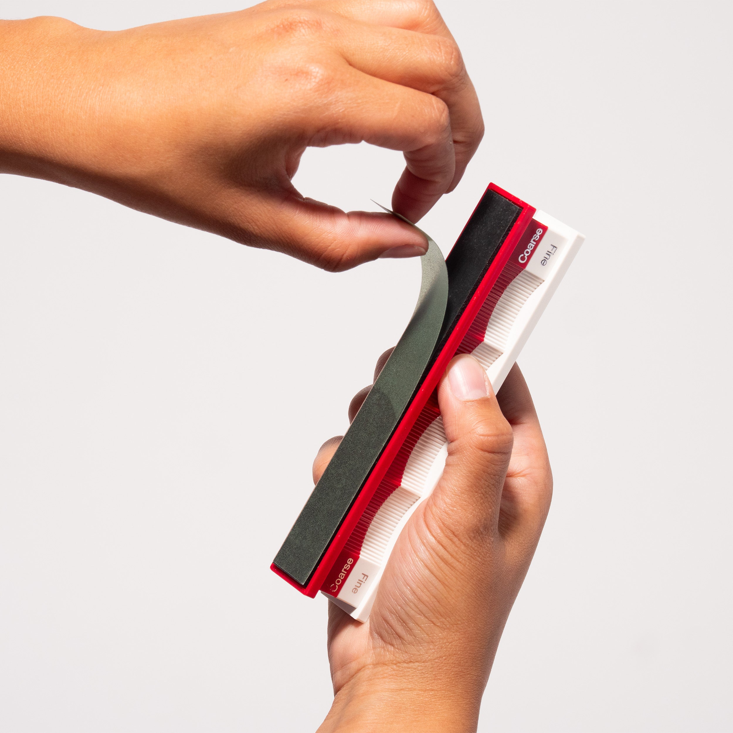 Edge Kit Ultimate Convex kit in hands at close-up from front angle, showing multiple red and white convex edge handles containing lapping films of various grits for shaping and polishing convex knife bevels.
