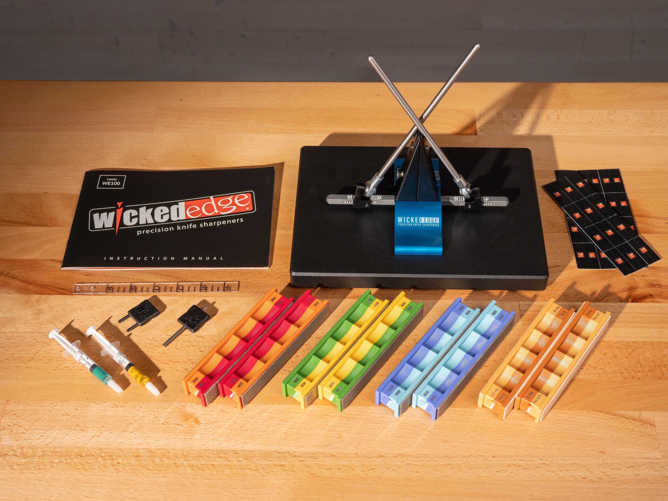 Pro-Pack I sharpening kit with colored stone handles and accessories on wooden surface at close-up from overhead angle.